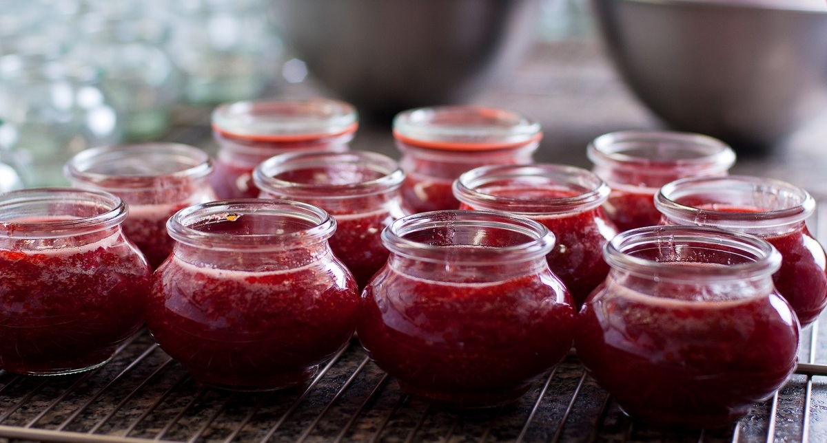 Pots alignés remplis de confiture de fruits rouges en phase de refroidissement