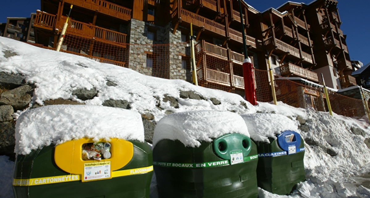 Bacs de collecte jaune, vert et bleu situés au bas des résidences tourisme en station de ski