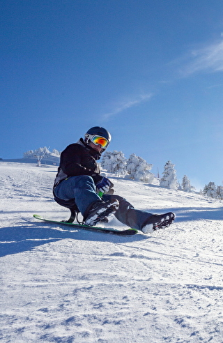 Un homme faisant de la luge sur une piste aménagée à Villards de Lans, sous un beau soleil, avec le sourire