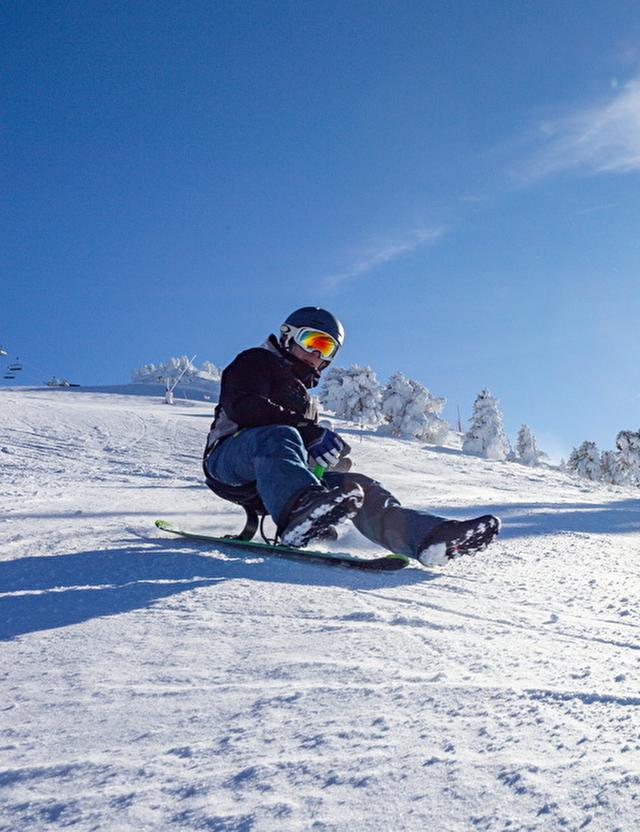 Un homme faisant de la luge sur une piste aménagée à Villards de Lans, sous un beau soleil, avec le sourire