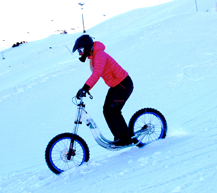 Personne équipée d'un casque effectuant une descente de XBike sur la neige en montagne