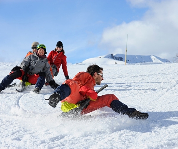 Groupe de personnes effectuant une descente en luge sur la neige en montagne