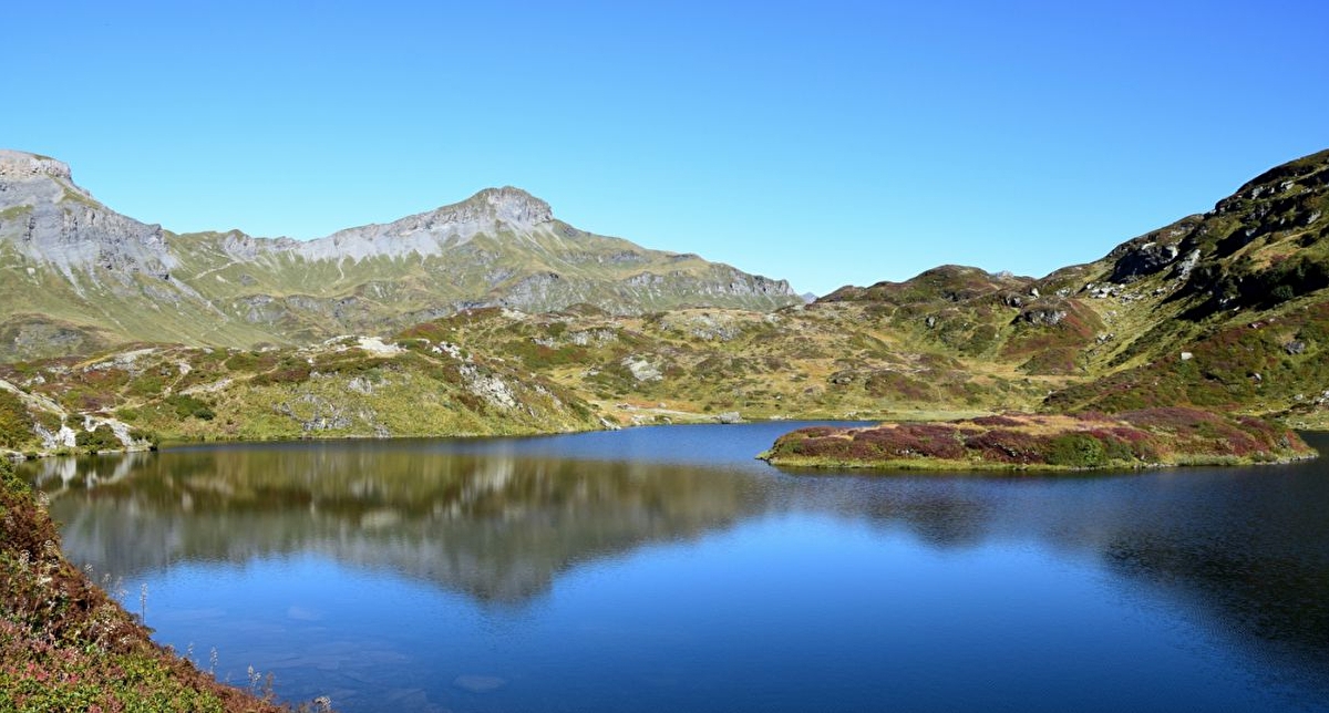 Vue sur un lac de montagne en automne où les montagnes se reflètent sur l'eau
