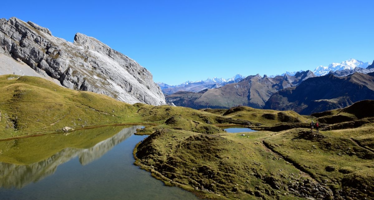 Vue sur un lac de montagne entouré de pics et sommets pour certains enneigés