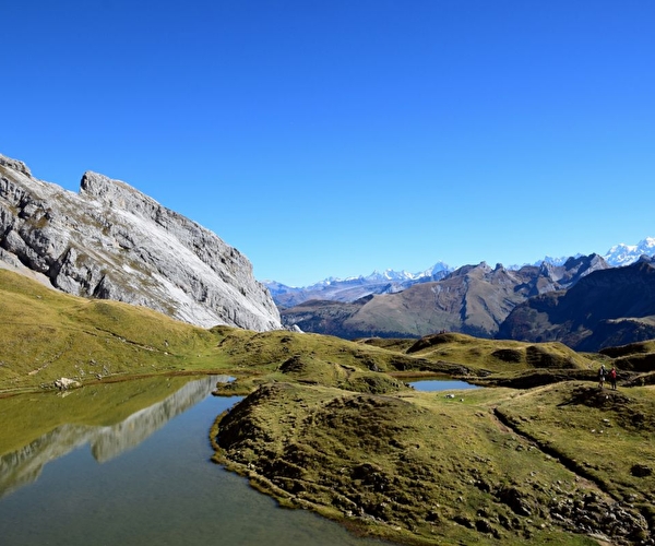 Vue sur un lac de montagne entouré de pics et sommets pour certains enneigés
