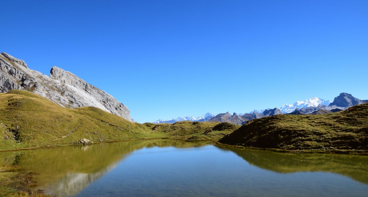 Vue sur un lac de montagne en automne face aux sommets et pics parfois enneigés