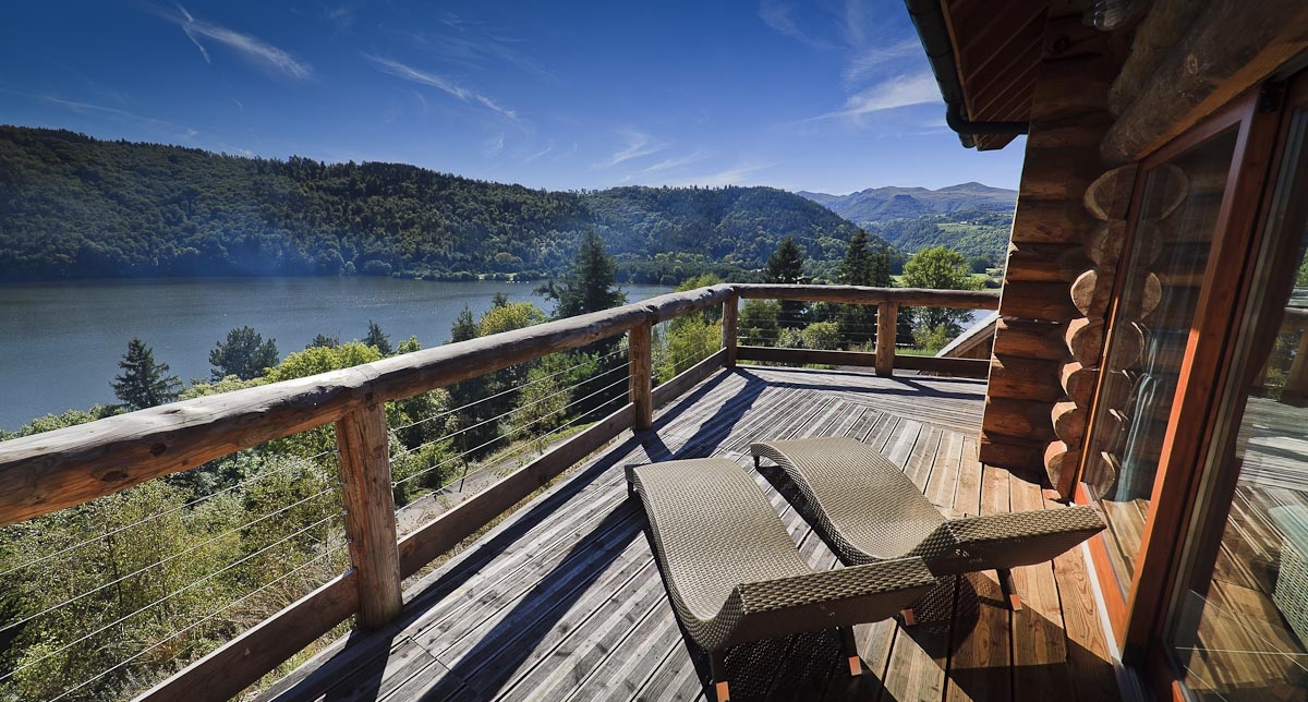 Terrasse en bois attenante au chalet avec bains de soleil pour profiter du lac et du panorama sur les montagnes