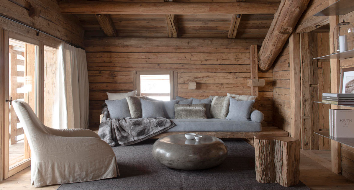 Espace détente et salon dans le Chalet 1864 avec canapé, fauteuils, table basse et bibliothèque attenante