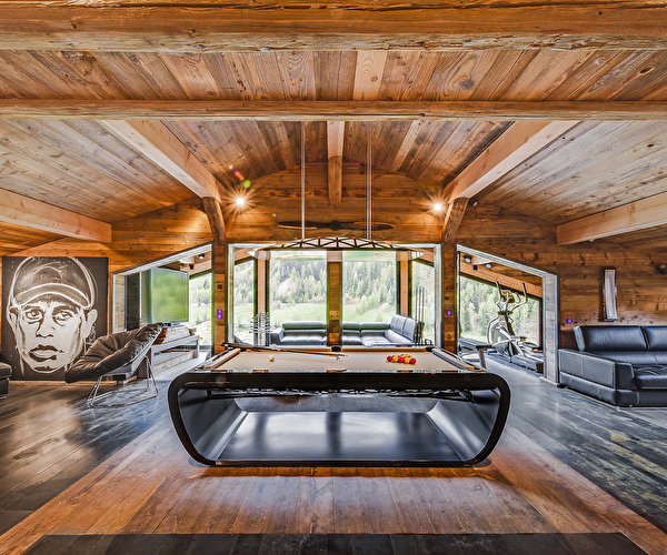 Vue intérieure du Chalet Quezac en bois et du salon proposant billard et meubles modernes