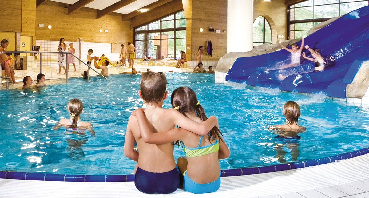 Vue sur la piscine intérieure d'un centre aqualudique avec ses grands tobboggans aquatiques