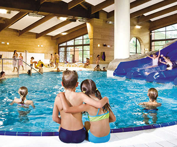 Vue sur la piscine intérieure d'un centre aqualudique avec ses grands tobboggans aquatiques