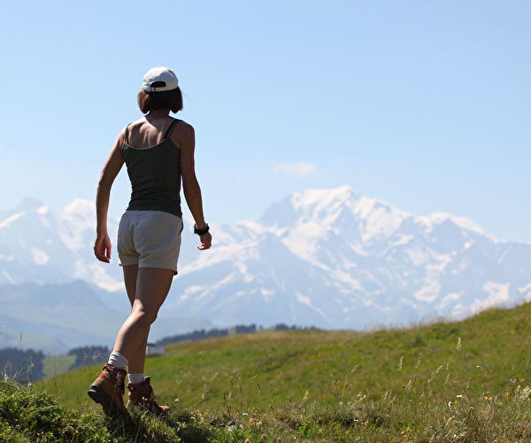 Femme habillée en tenue d'été portant une casquette lors d'une randonnée en montagne l'été sous le soleil