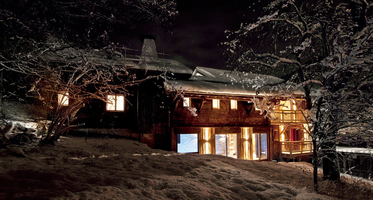 Vue extérieure sur un chalet de bois éclairé et recouvert de neige