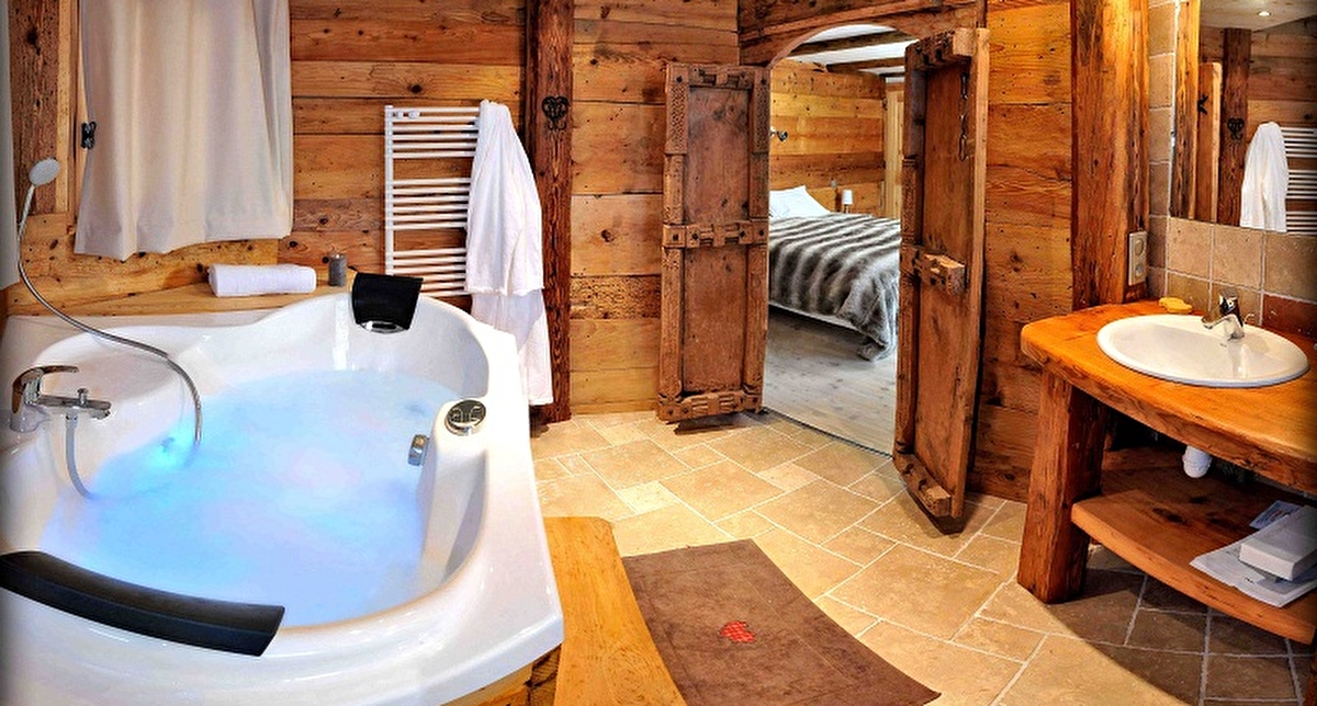 Vue intérieure d'une salle de bain attenante à une chambre dans un chalet de montagne avec baignoire à remous