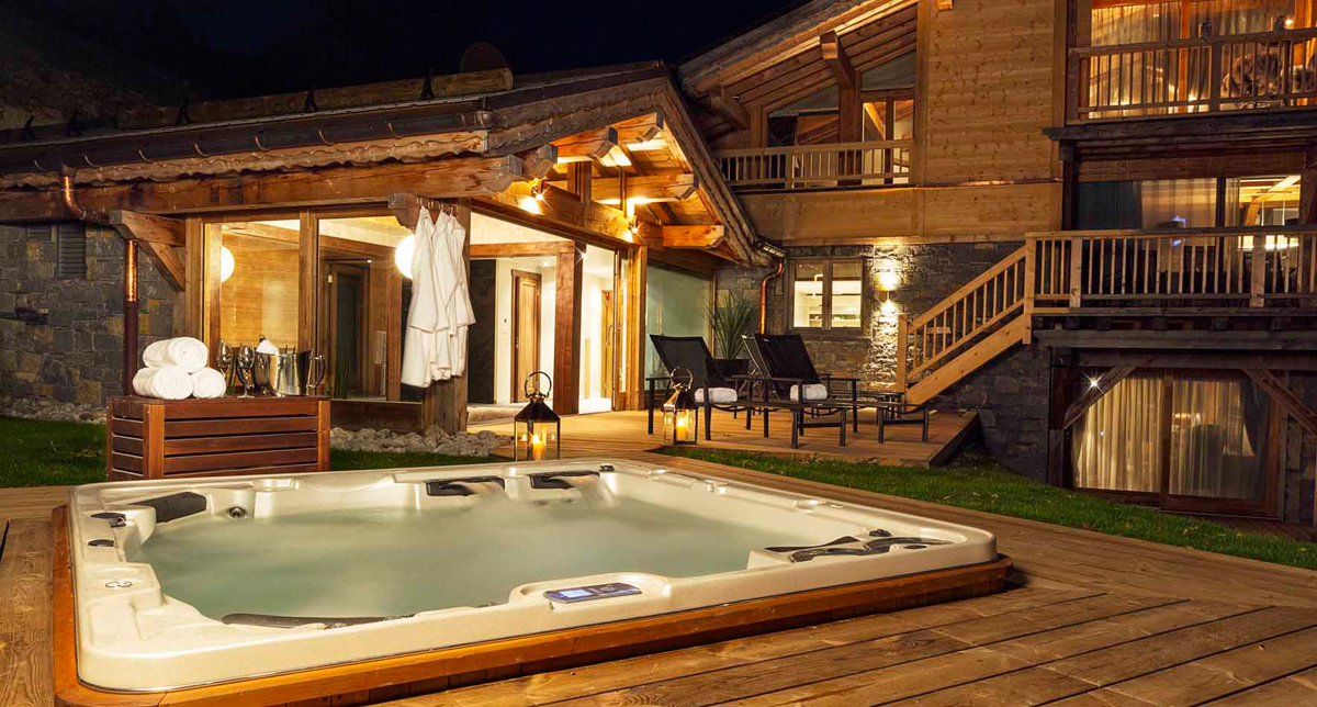 Vue extérieure sur un chalet en bois proposant un jacuzzi extérieur sur terrasse
