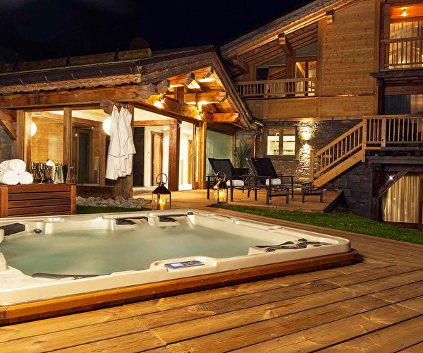 Vue extérieure sur un chalet en bois proposant un jacuzzi extérieur sur terrasse