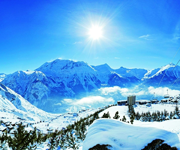 Vue panoramique sur une station de ski en hiver, sa vallée, son télécabine et ses montagnes enneigées