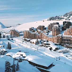 Vue aérienne d'une station de ski enneigée avec immeubles et sommets
