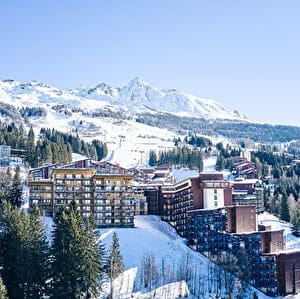 Vue du ciel sur une station de ski enneigée avec bâtiments et pistes de ski